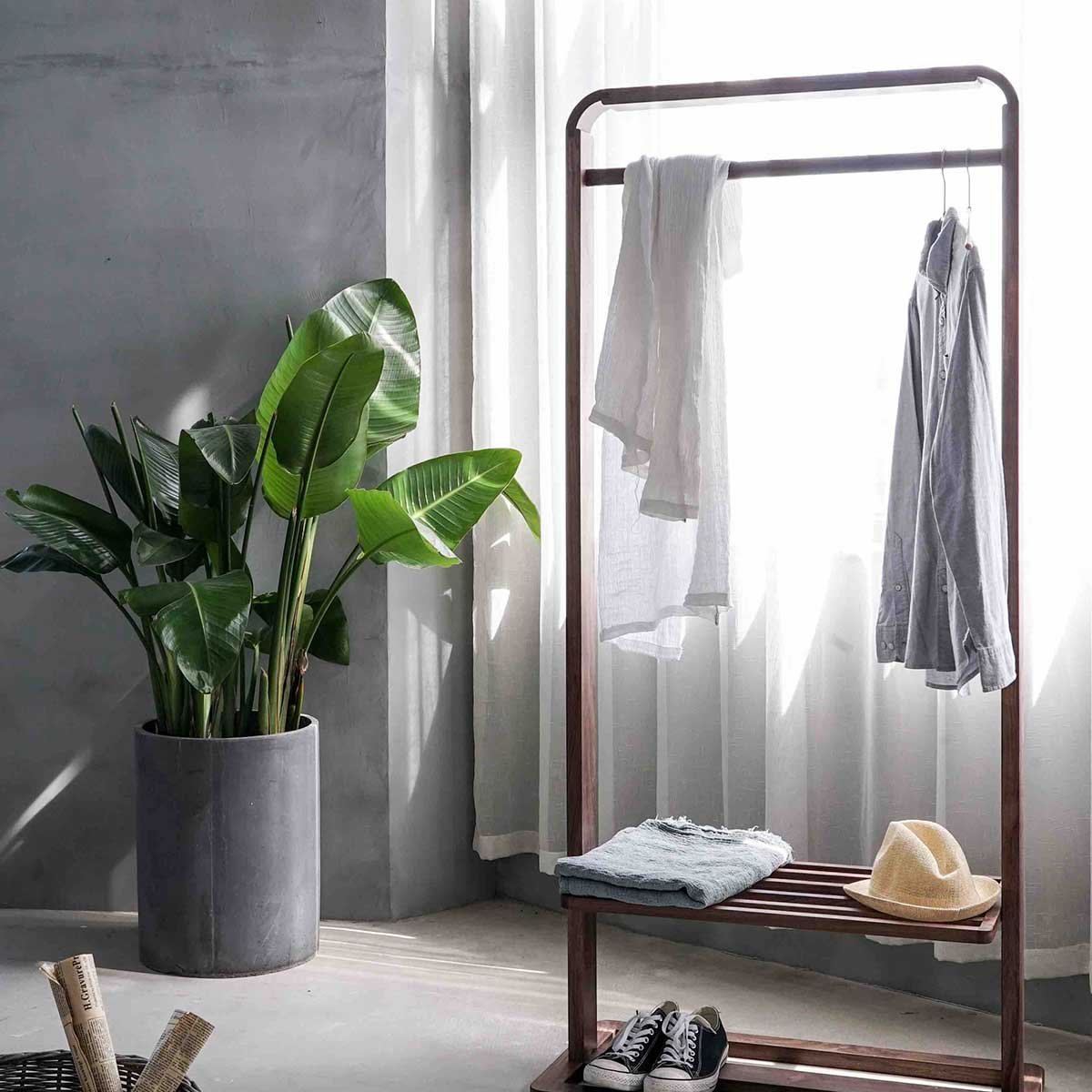 Garments hanging in the VESTRA atelier beside a window and a potted plant